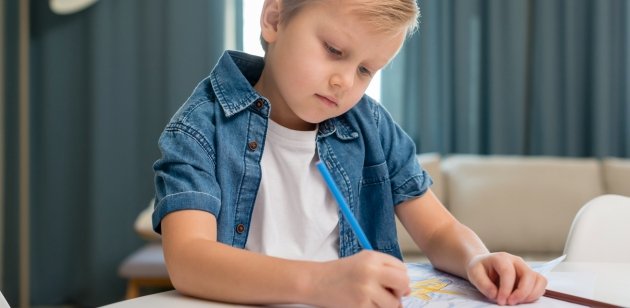 A young child practicing cursive writing in a notebook at Dreamztree, Kuwait